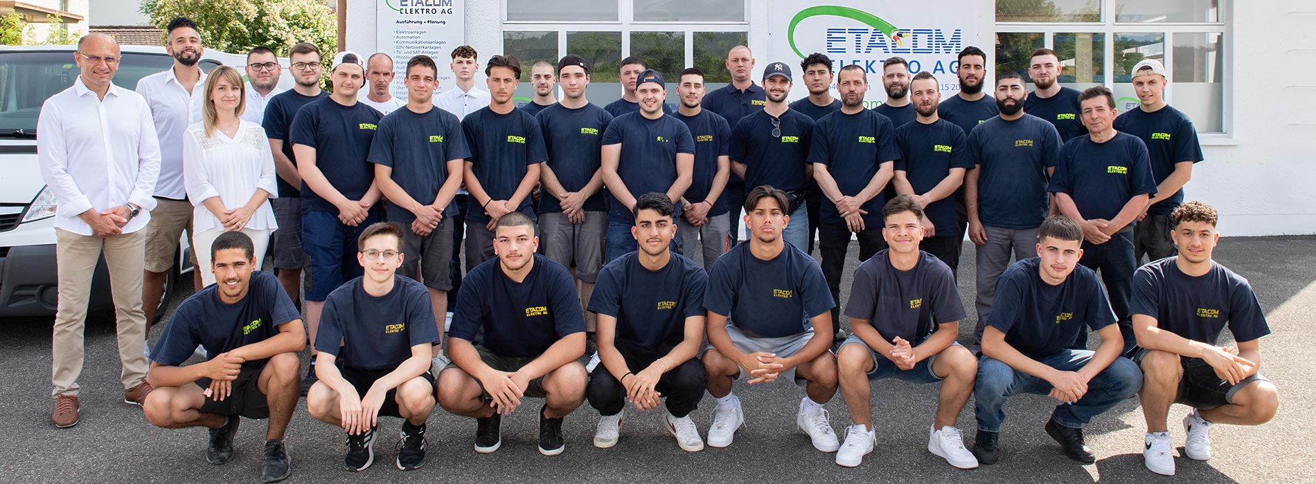 Das ETACOM-Team in Firmenshirts vor dem Firmengebäude
